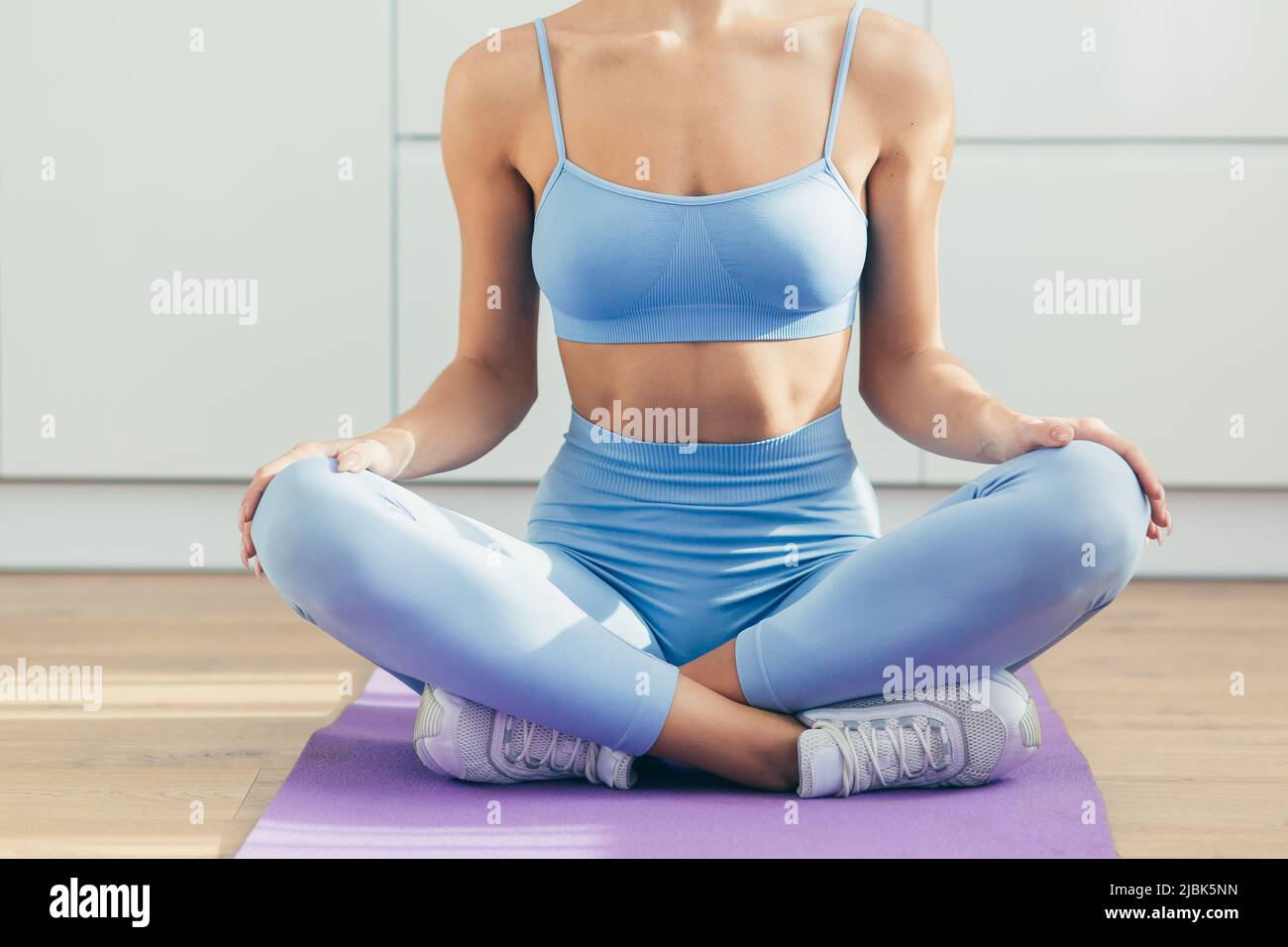 Close up photo of body part, young fitness woman sitting in lotus position, doing yoga at home on the podium Stock Photo