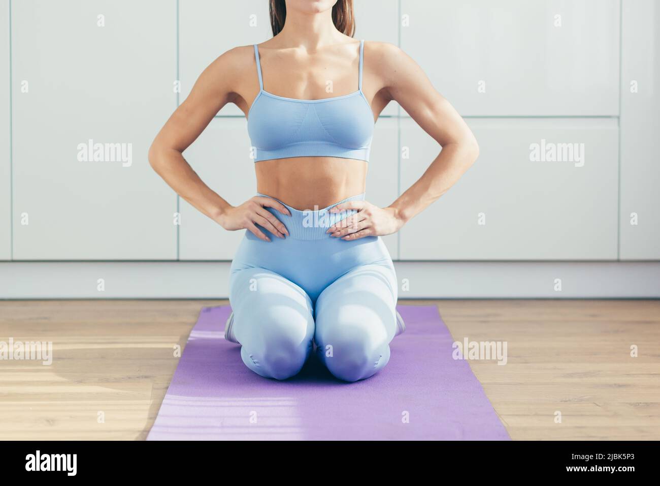 Close up photo part of the body of a young beautiful sports woman sitting on a mat at home, doing yoga, sports Stock Photo