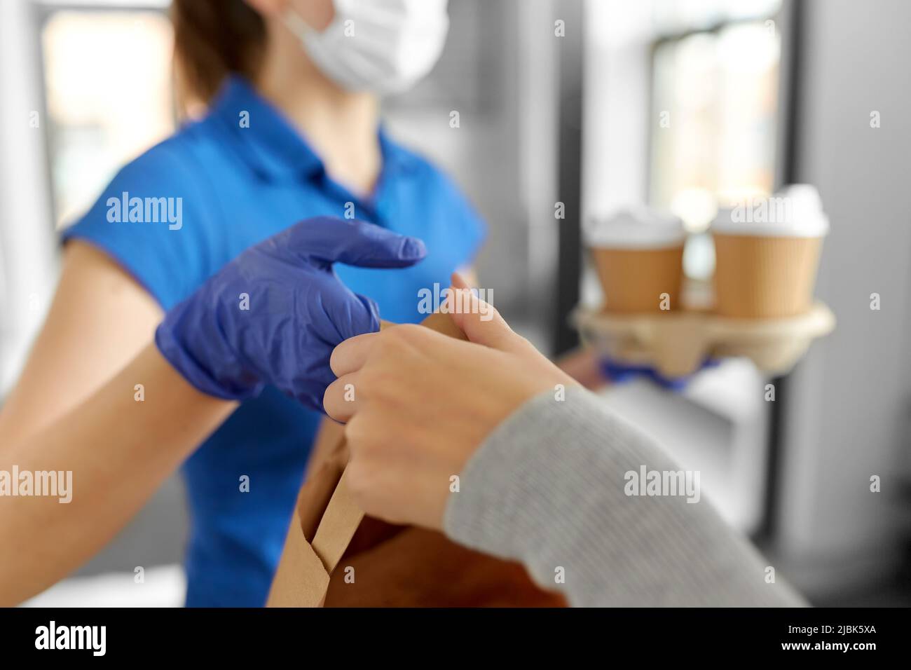 delivery girl in mask giving paper bag to woman Stock Photo - Alamy