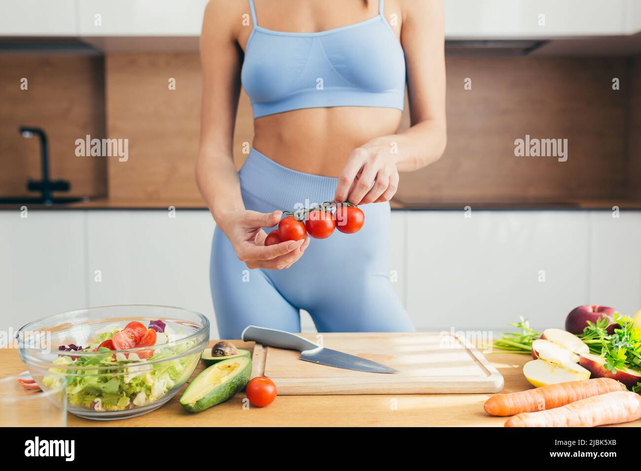 Close up photo, body part, hands of young fitness woman cutting fresh vegetables on kitchen salad at home Stock Photo