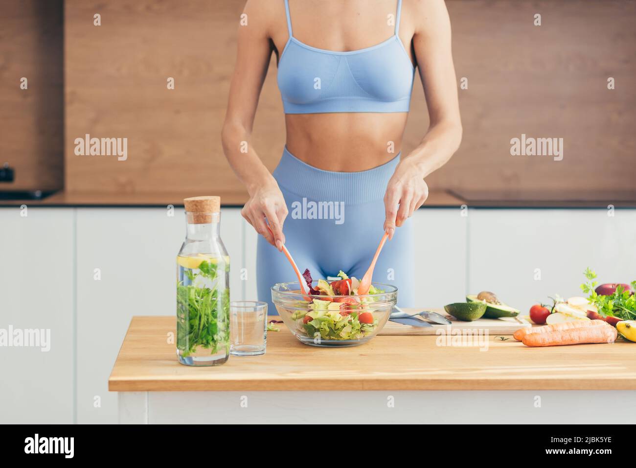 Close up photo, body part, hands of young fitness woman making salad with fresh vegetables and fresh detox drink in kitchen at home Stock Photo