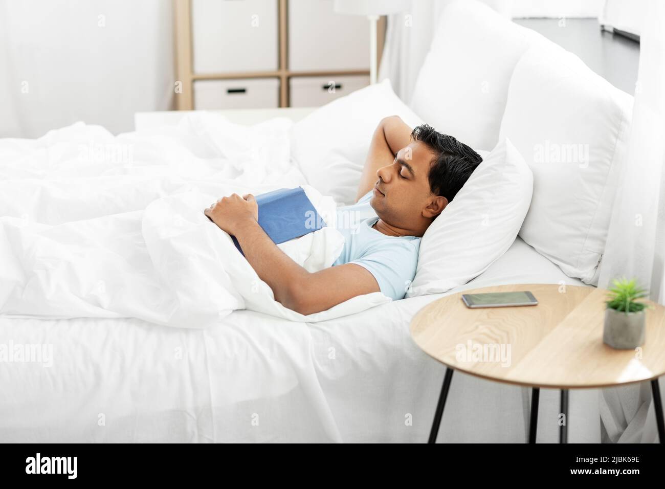indian man with book sleeping in bed at home Stock Photo