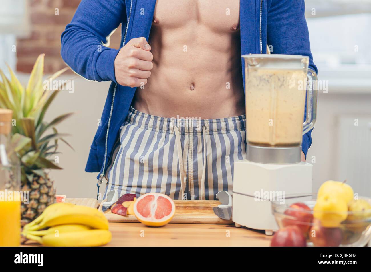 Close up photo, part of body. Male athlete preparing, detox in a blender , fruit salad and fresh juice at home in the kitchen, Stock Photo