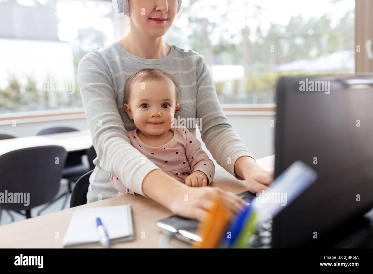 mother with baby working on laptop at home office Stock Photo
