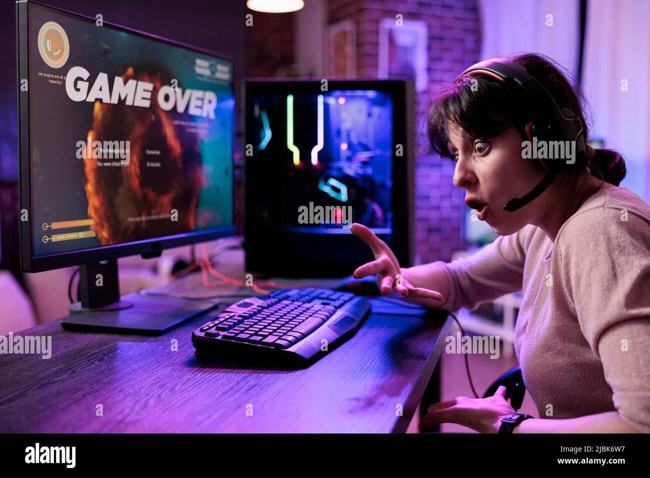 Frustrated woman losing video games tournament on pc, feeling sad about lost shooting gameplay competititon. Female gamer playing online rpg action championship on live stream. Stock Photo