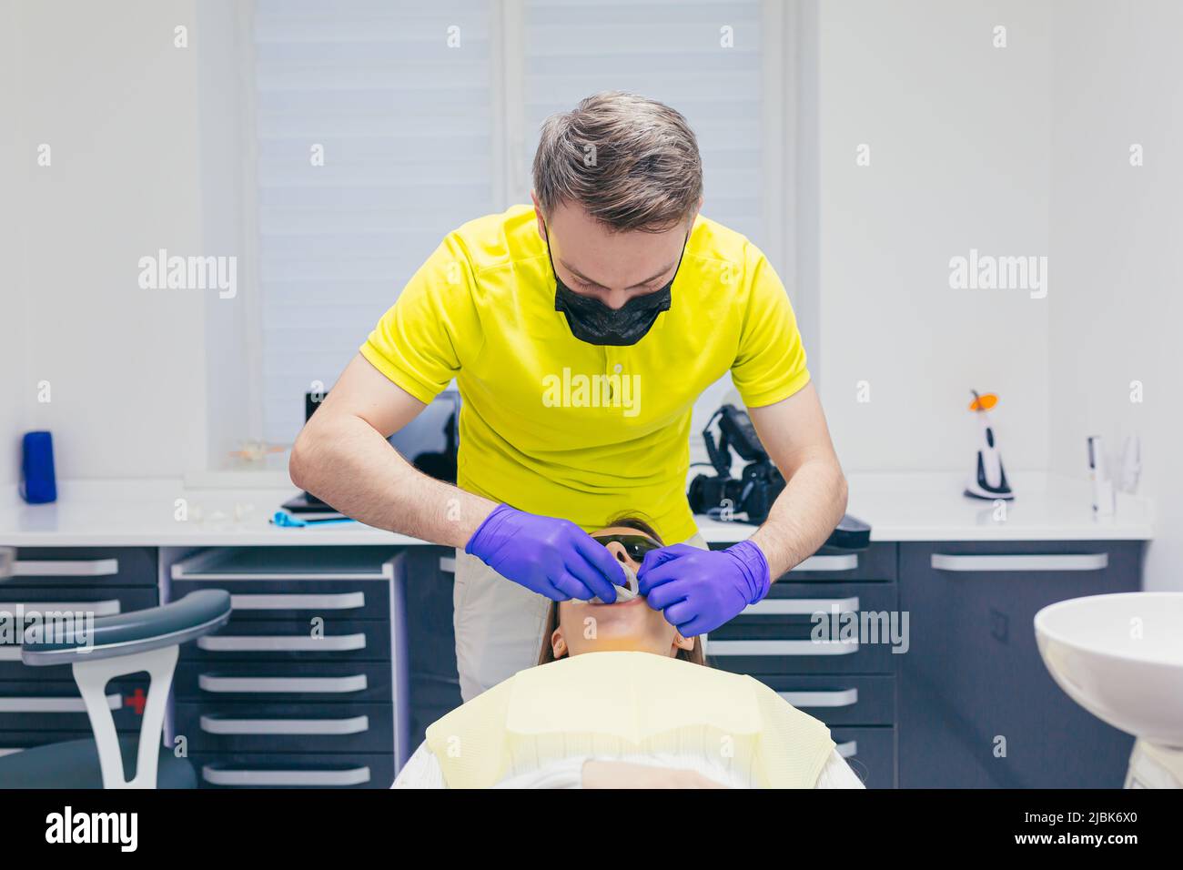 The dentist puts a cap on the mouth of a young female patient lying in