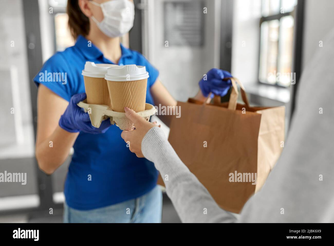 delivery girl in mask giving paper bag to woman Stock Photo - Alamy