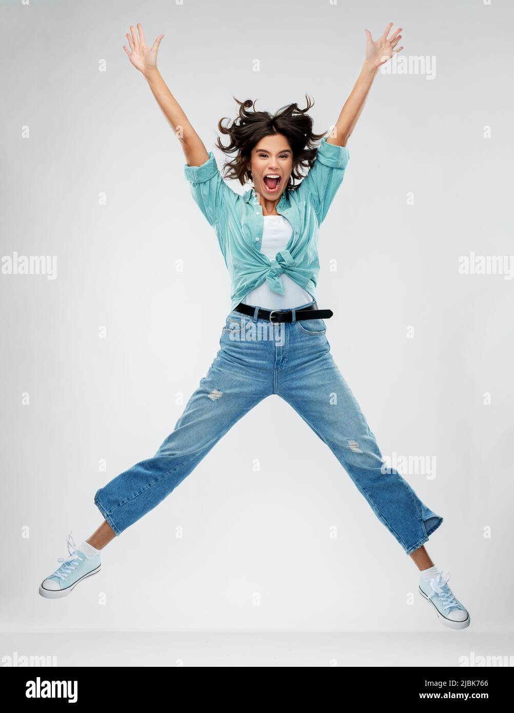 happy young woman jumping over grey background Stock Photo