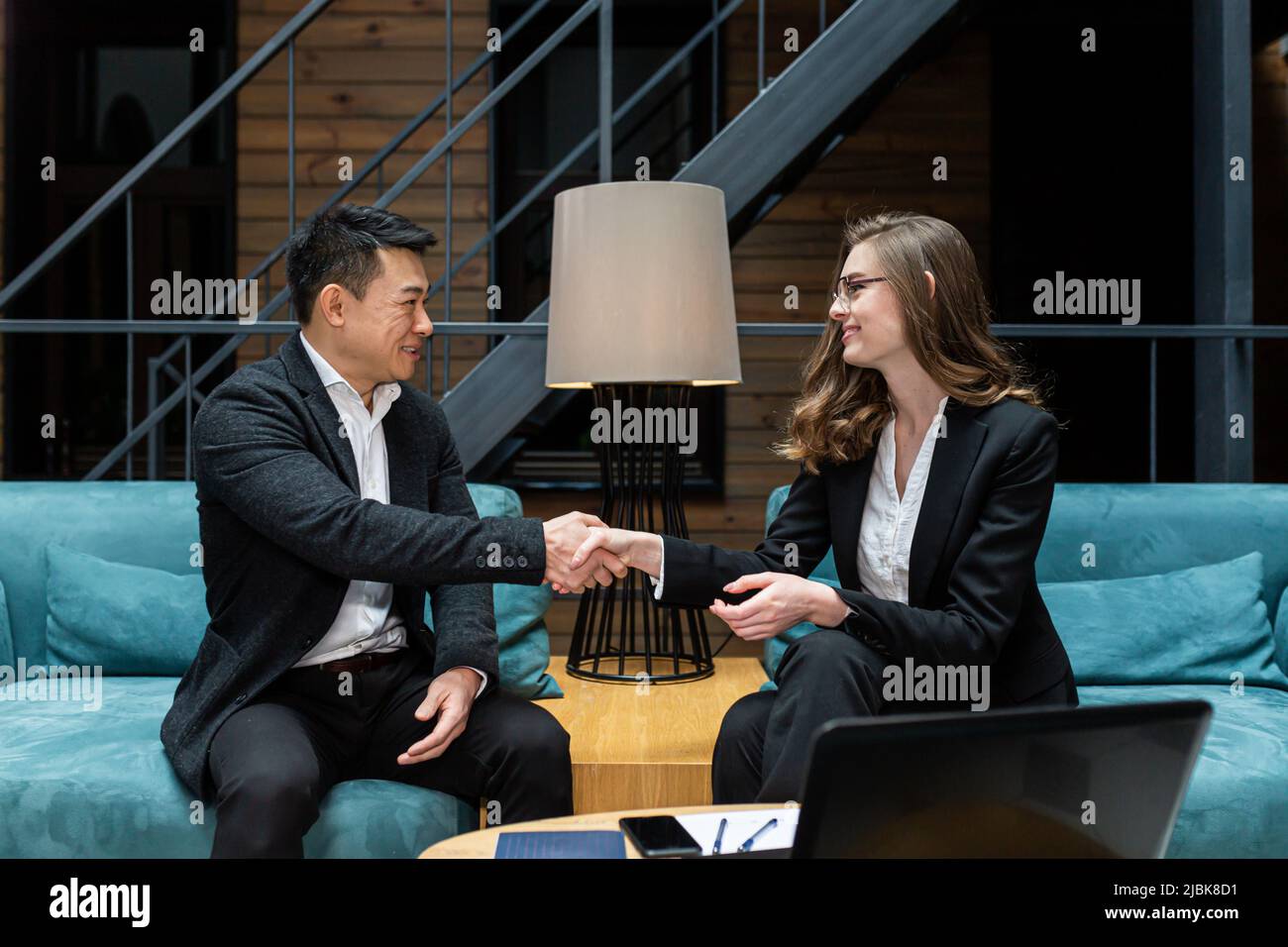 A man and a woman end a business meeting, shake hands, and rejoice in a successful deal Stock Photo