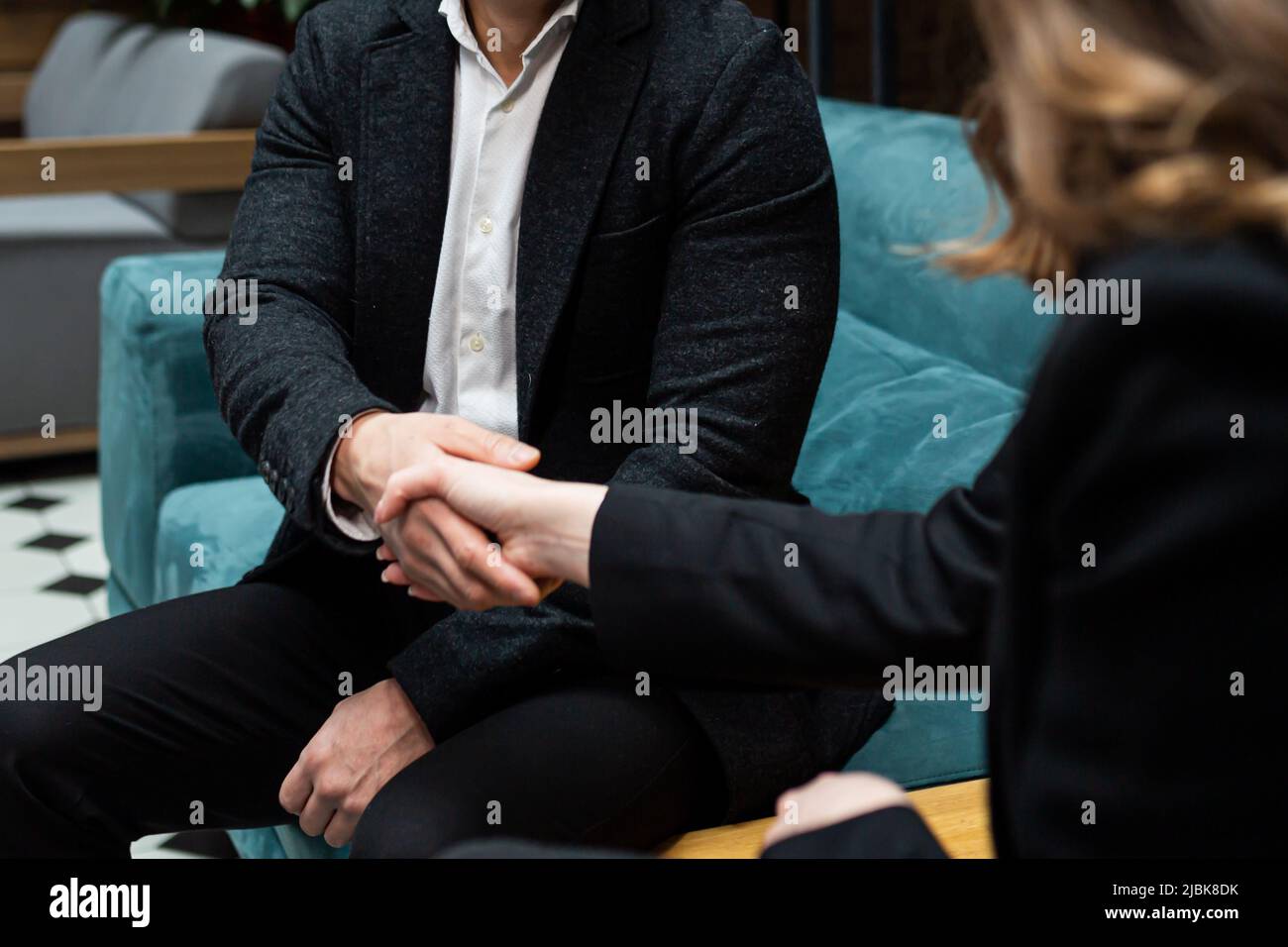 A man and a woman end a business meeting, shake hands, and rejoice in a