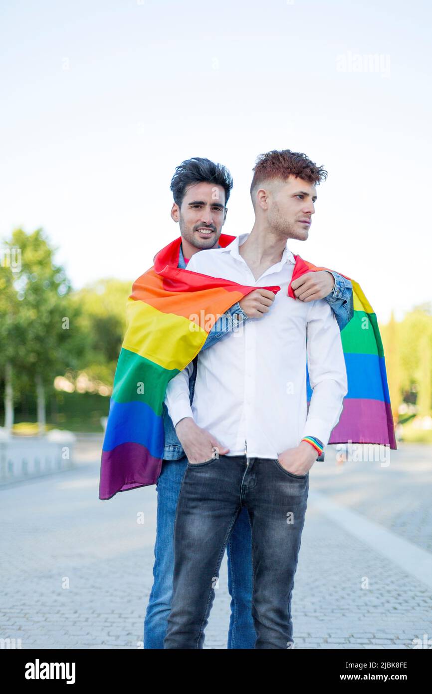 Gay couple embracing with LGBT pride flag outdoors. Relationship