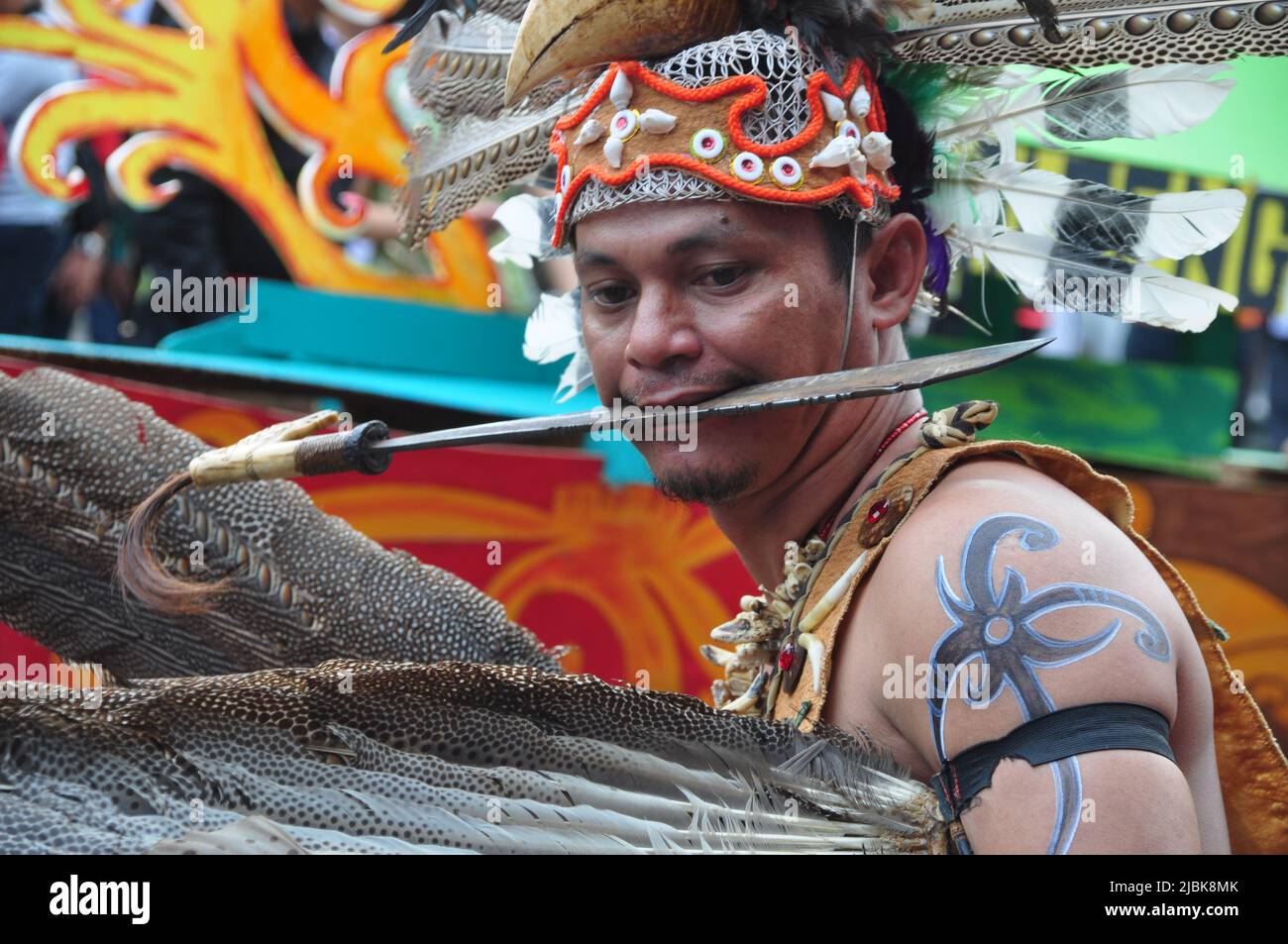 Jakarta, Indonesia - April 28, 2013 : A participant at the Dayak Festival in Jakarta, Indonesia, poses while biting Mandau, the Dayak traditional mach Stock Photo