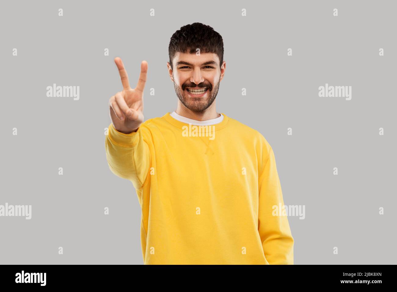 young man showing peace over grey background Stock Photo