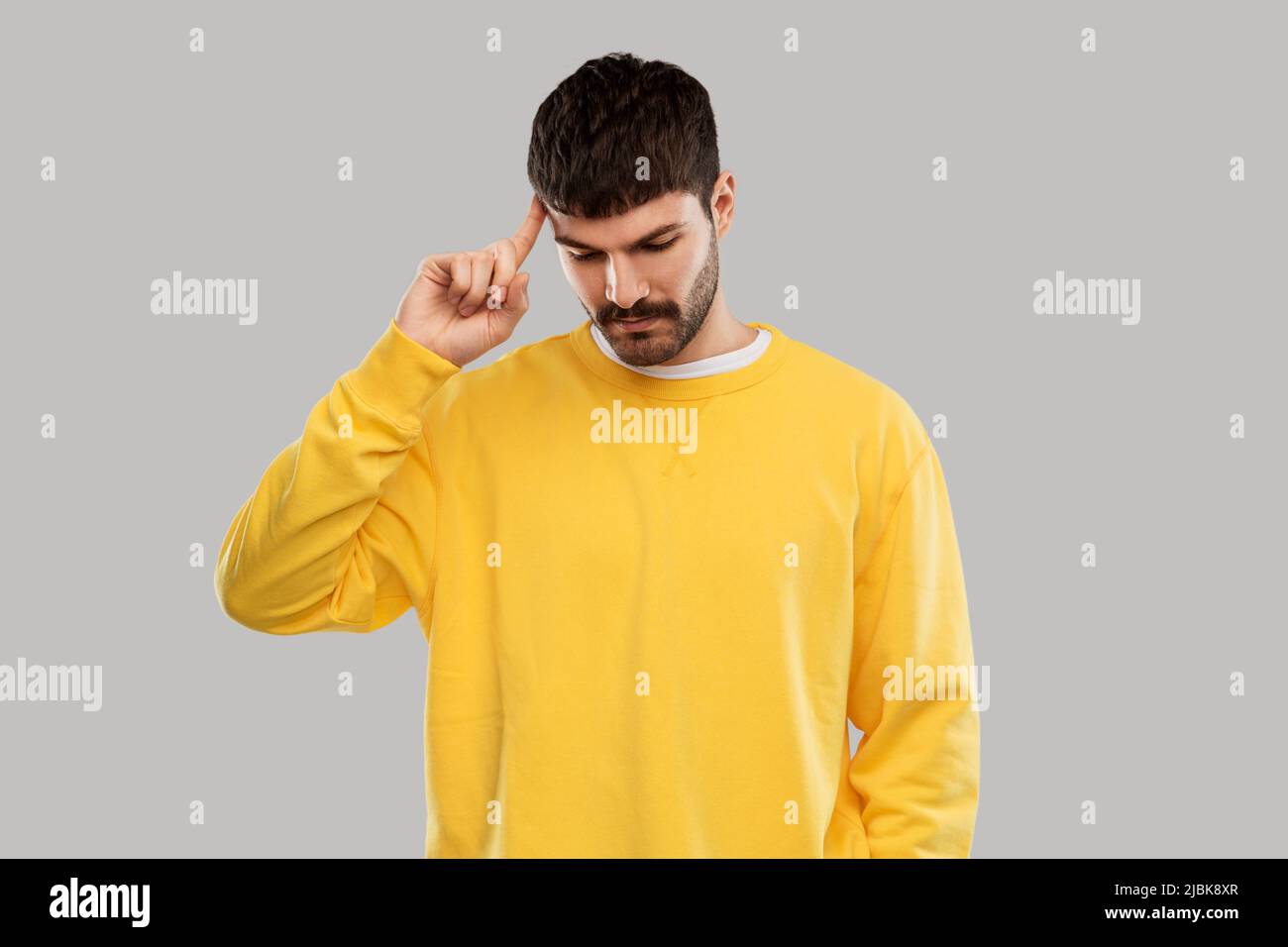thinking young man in yellow sweatshirt Stock Photo
