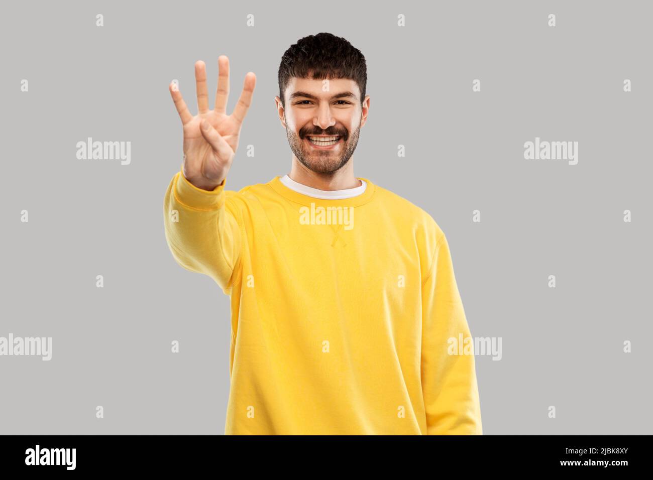 man in yellow sweatshirt showing three fingers Stock Photo