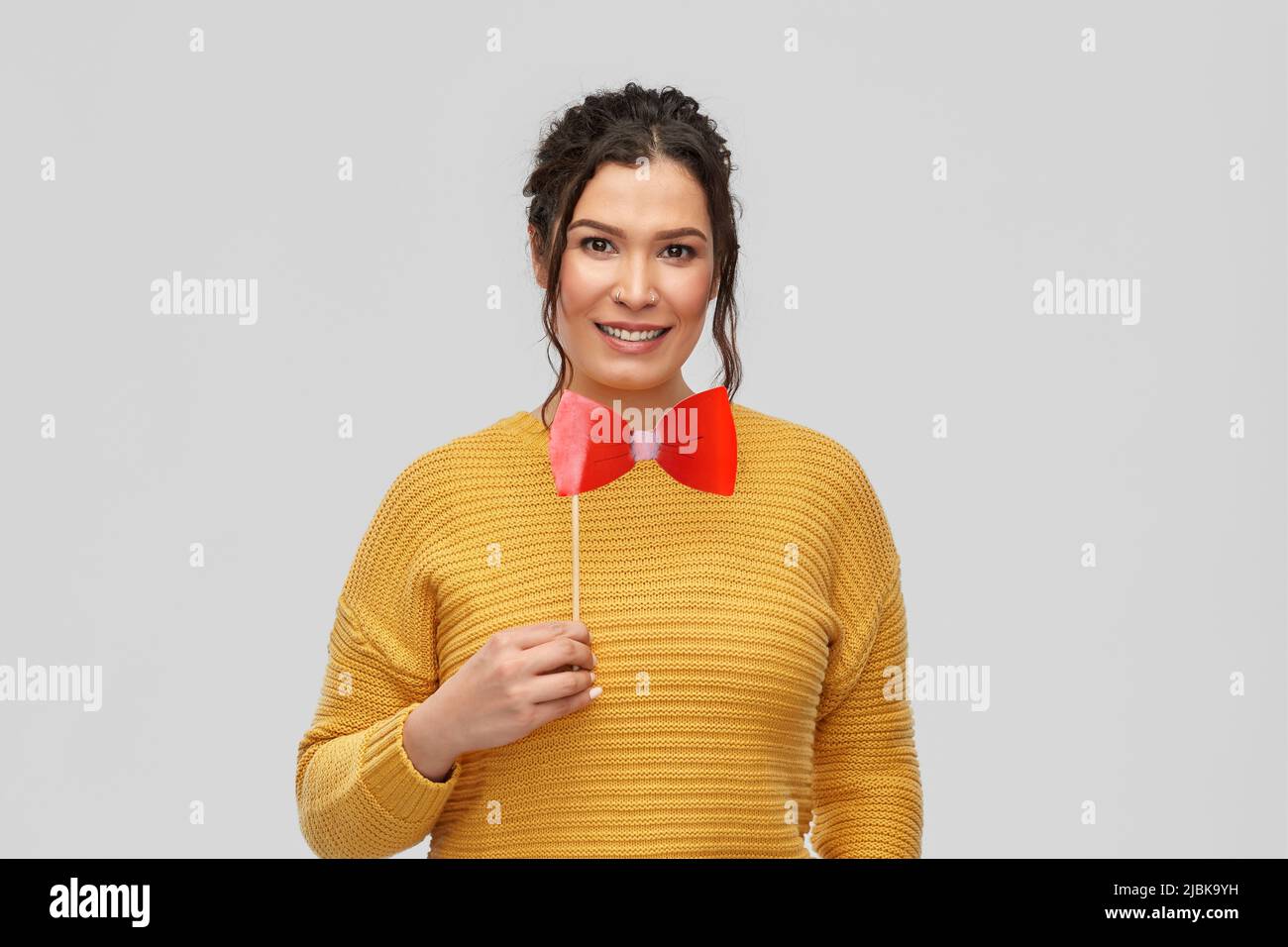 happy young woman with big red bowtie party prop Stock Photo