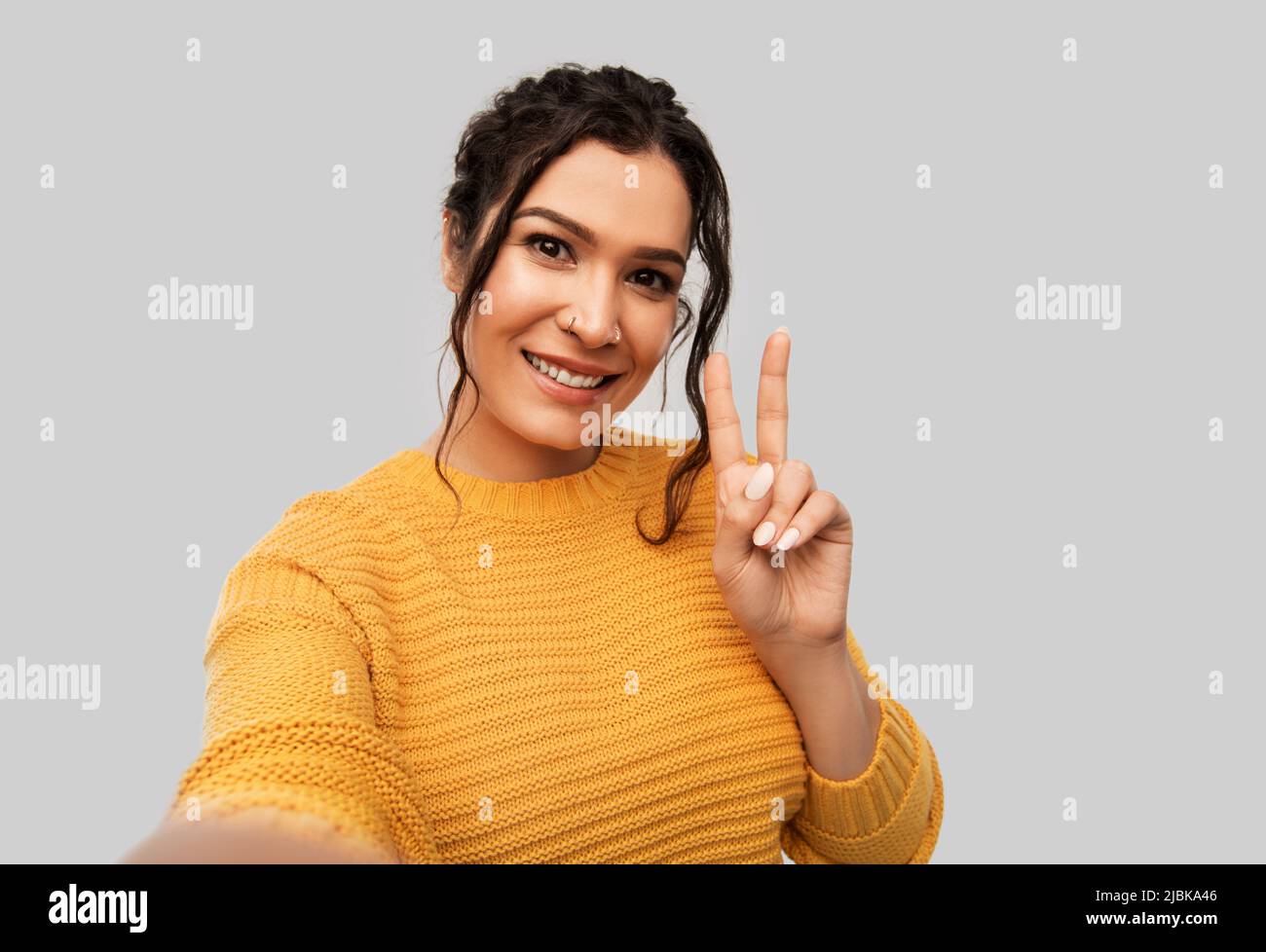 woman with pierced nose taking selfie shows peace Stock Photo