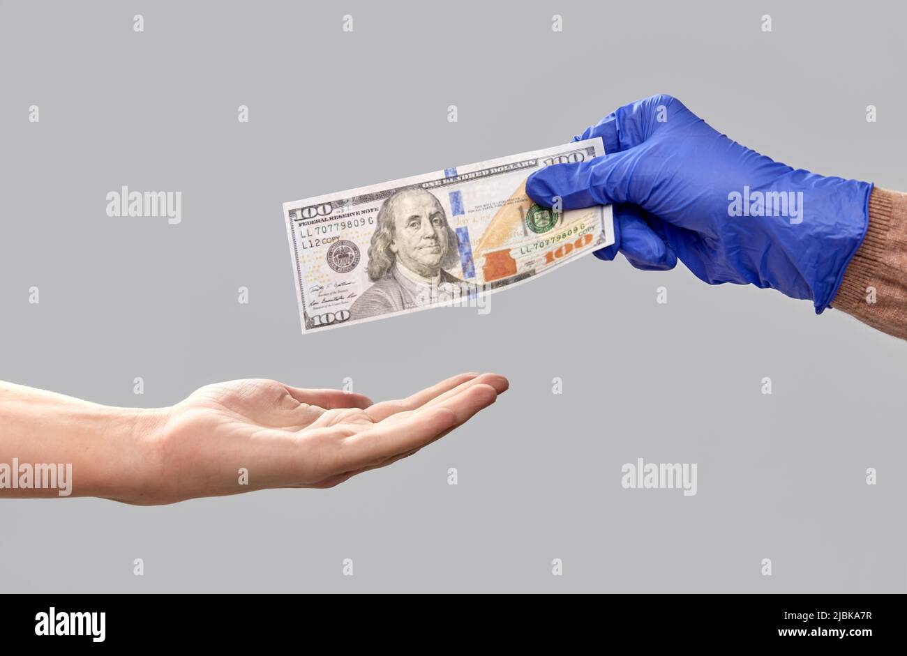 one hand in medical glove giving money to another Stock Photo