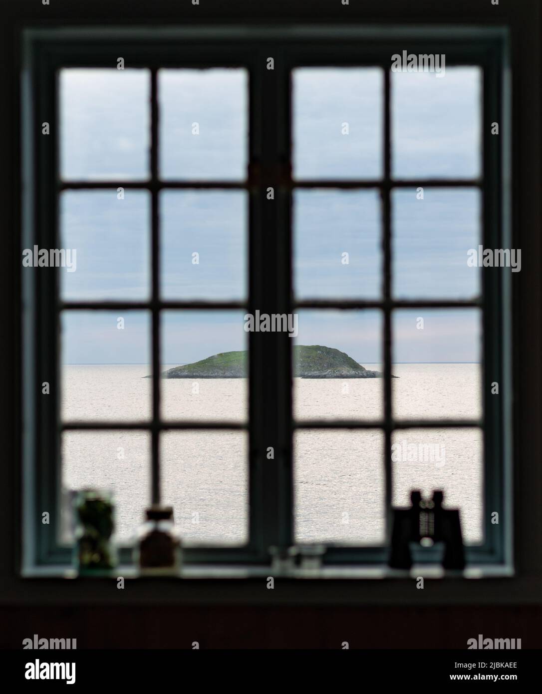 View with ocean, a island and the horison, seen through an old window. Photo taken from Kråkeslottet, Skaland, Senja. Stock Photo