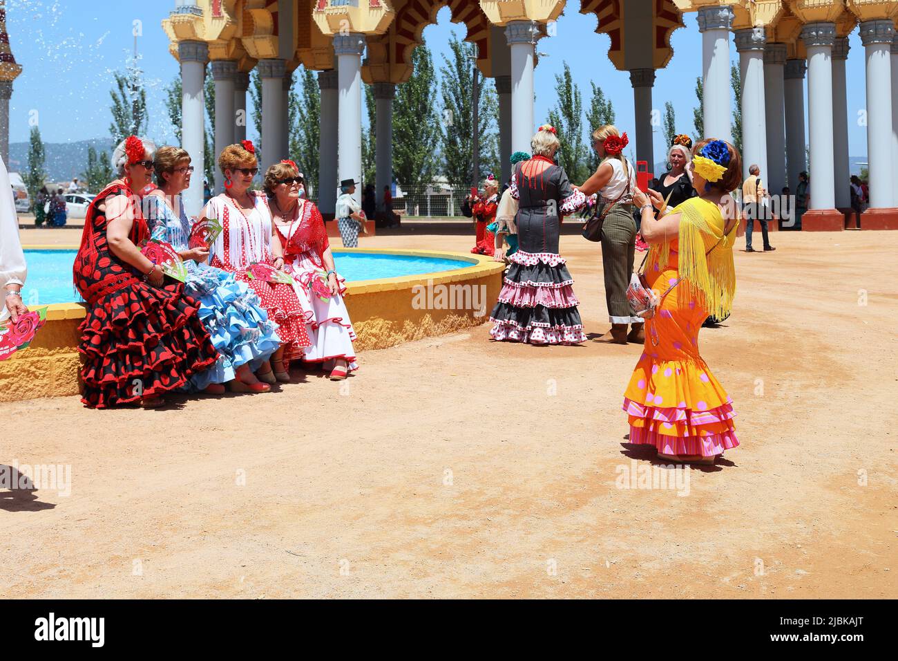 CORDOBA, SPAIN - MAY 23, 2017: Unidentified women in colorful national dresses take photos at the Feria festival site. Stock Photo