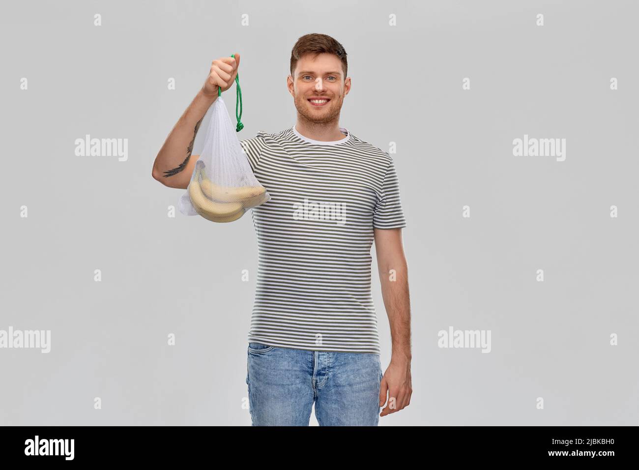 happy man holding reusable string bag with bananas Stock Photo