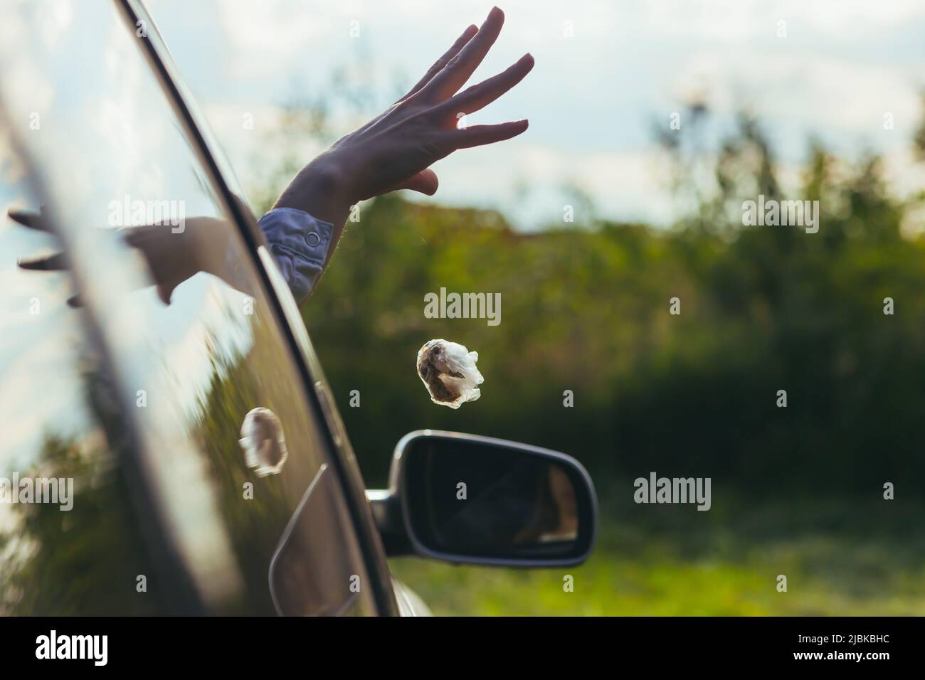 woman throws garbage out the car window Stock Photo