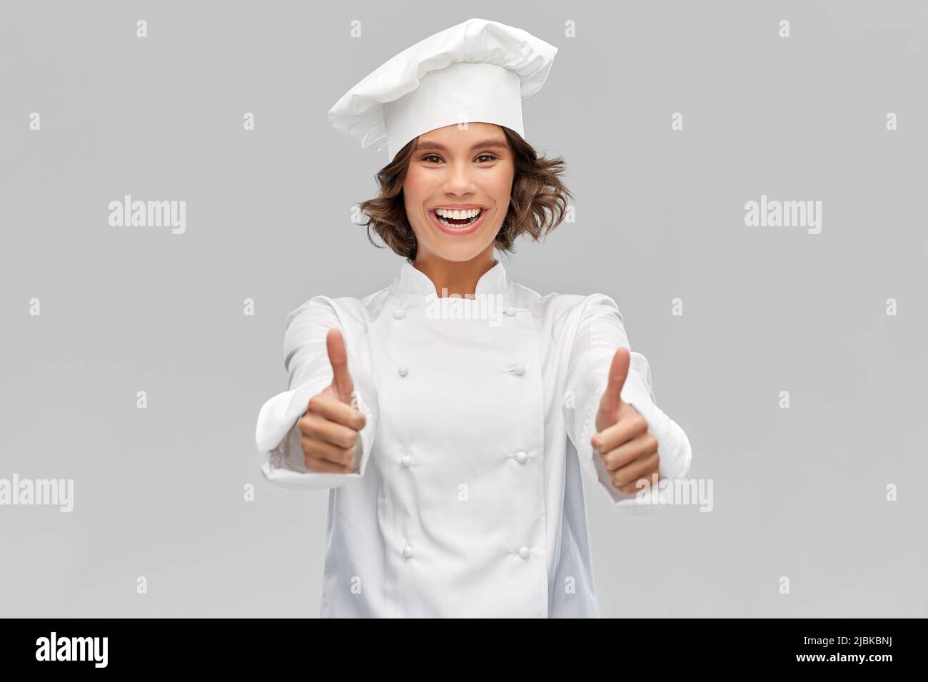 smiling female chef in toque showing thumbs up Stock Photo