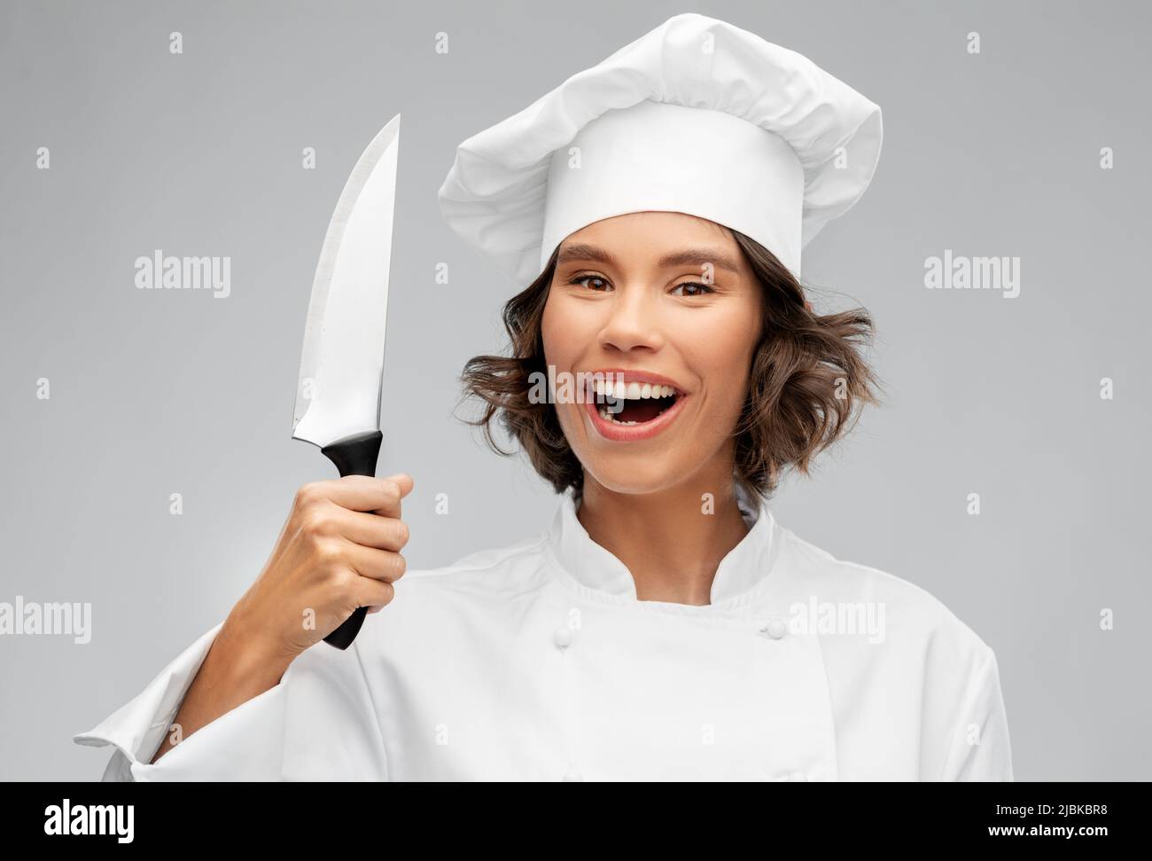 smiling female chef in toque with kitchen knife Stock Photo