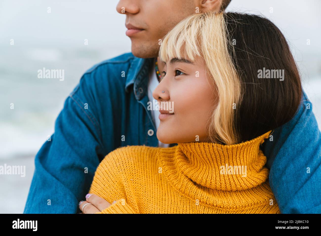 Multiracial young couple hugging while walking on beach Stock Photo