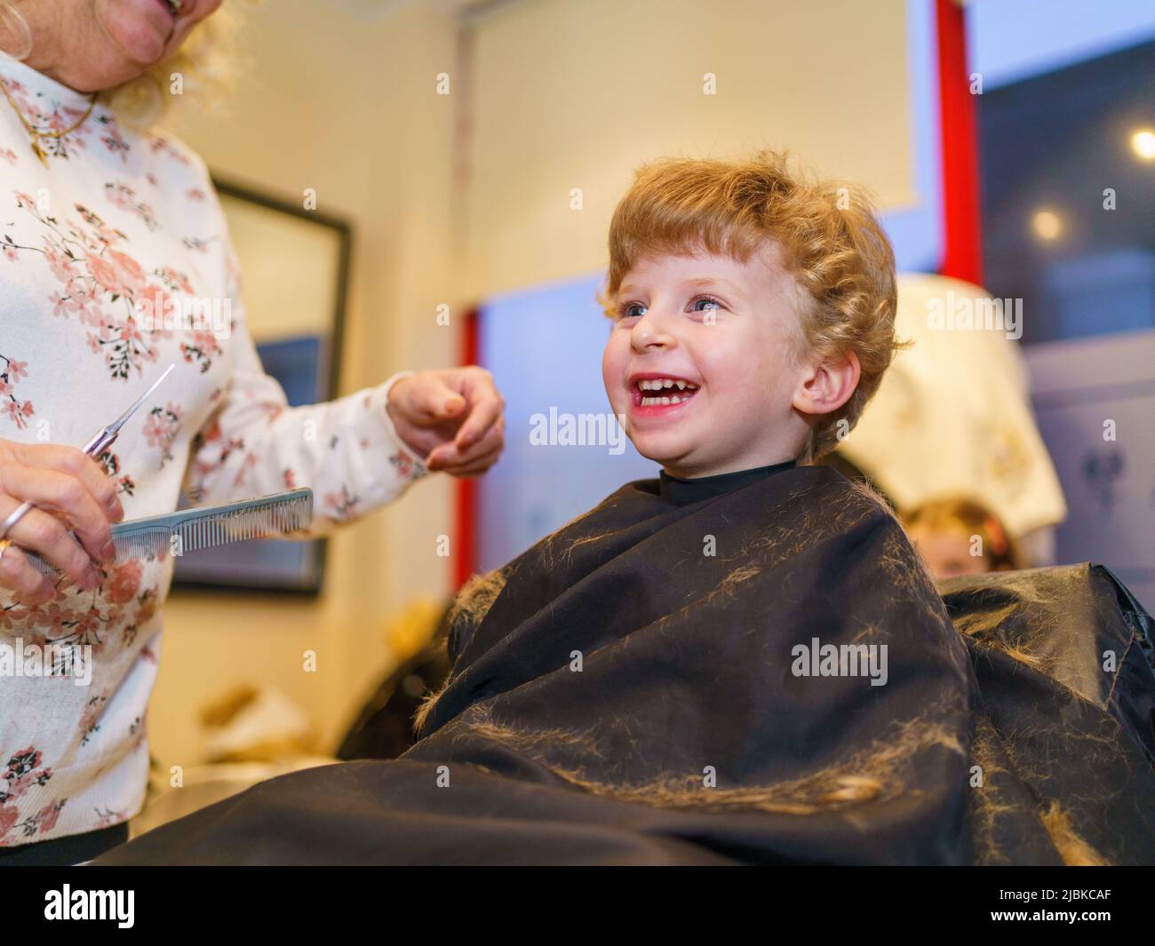 Two year old boy having a his hair cut at the hairdresser, UK Stock Photo
