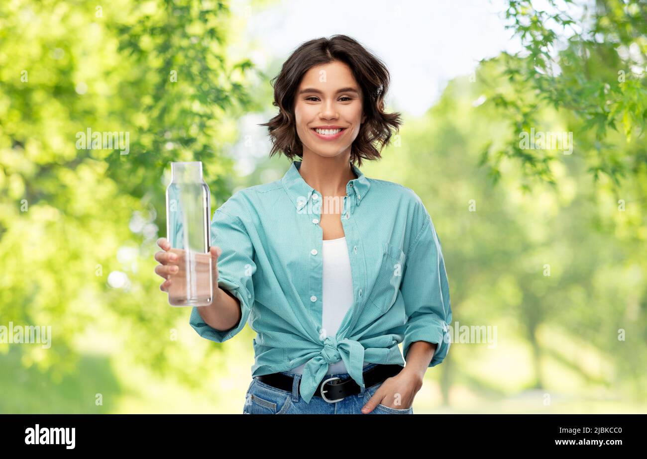 smiling young woman holding water in glass bottle Stock Photo