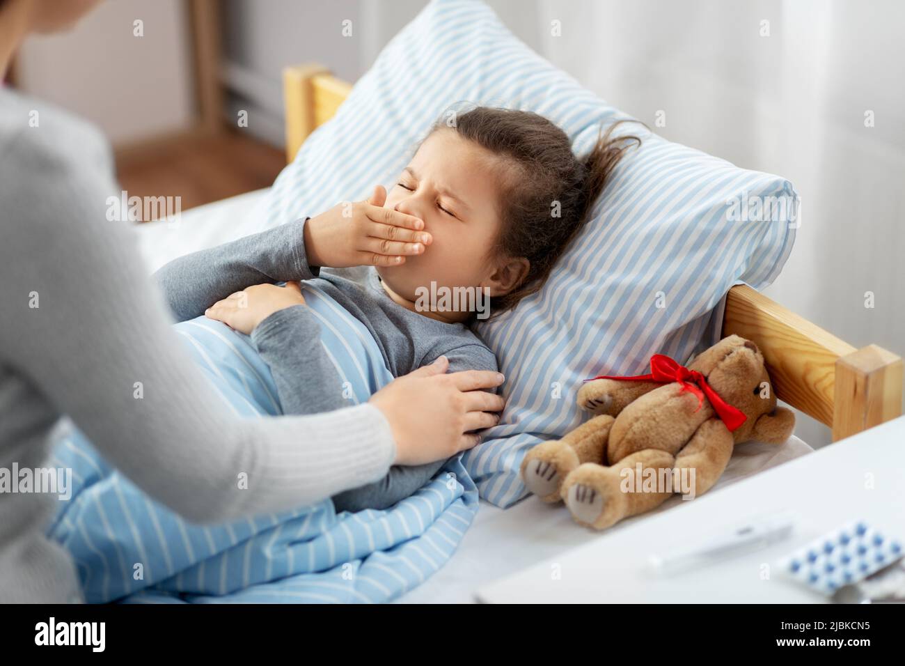 mother and sick little daughter in bed at home Stock Photo