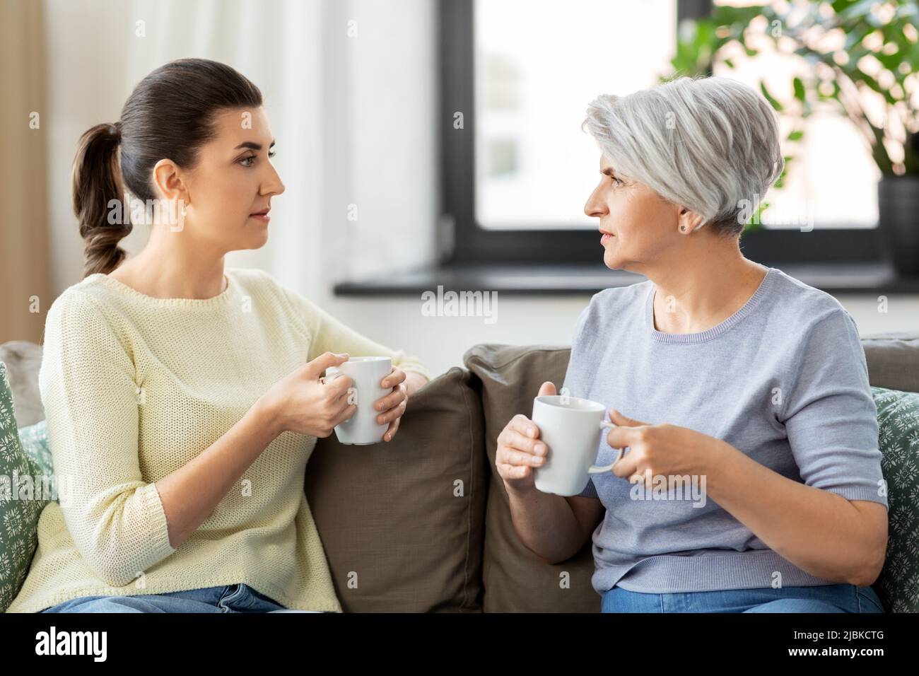 senior mother and adult daughter drinking coffee Stock Photo