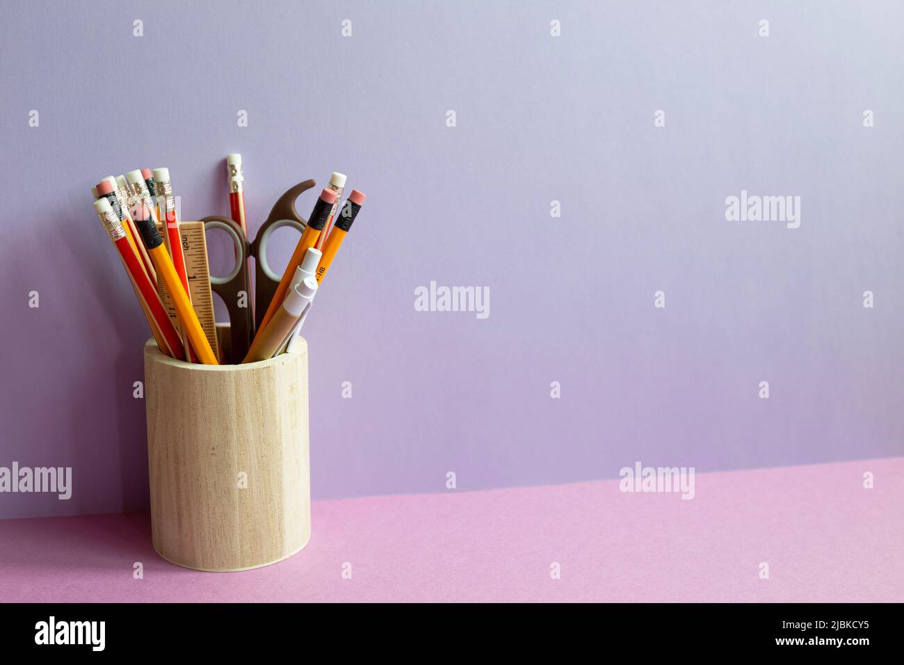 Pencils and various stationery in wooden holder on purple desk. purple wall background Stock Photo