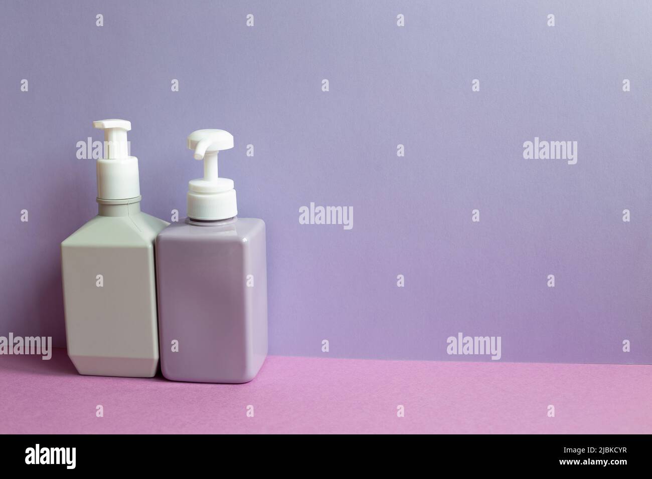 Plastic shampoo bottles on purple table. purple wall background Stock Photo
