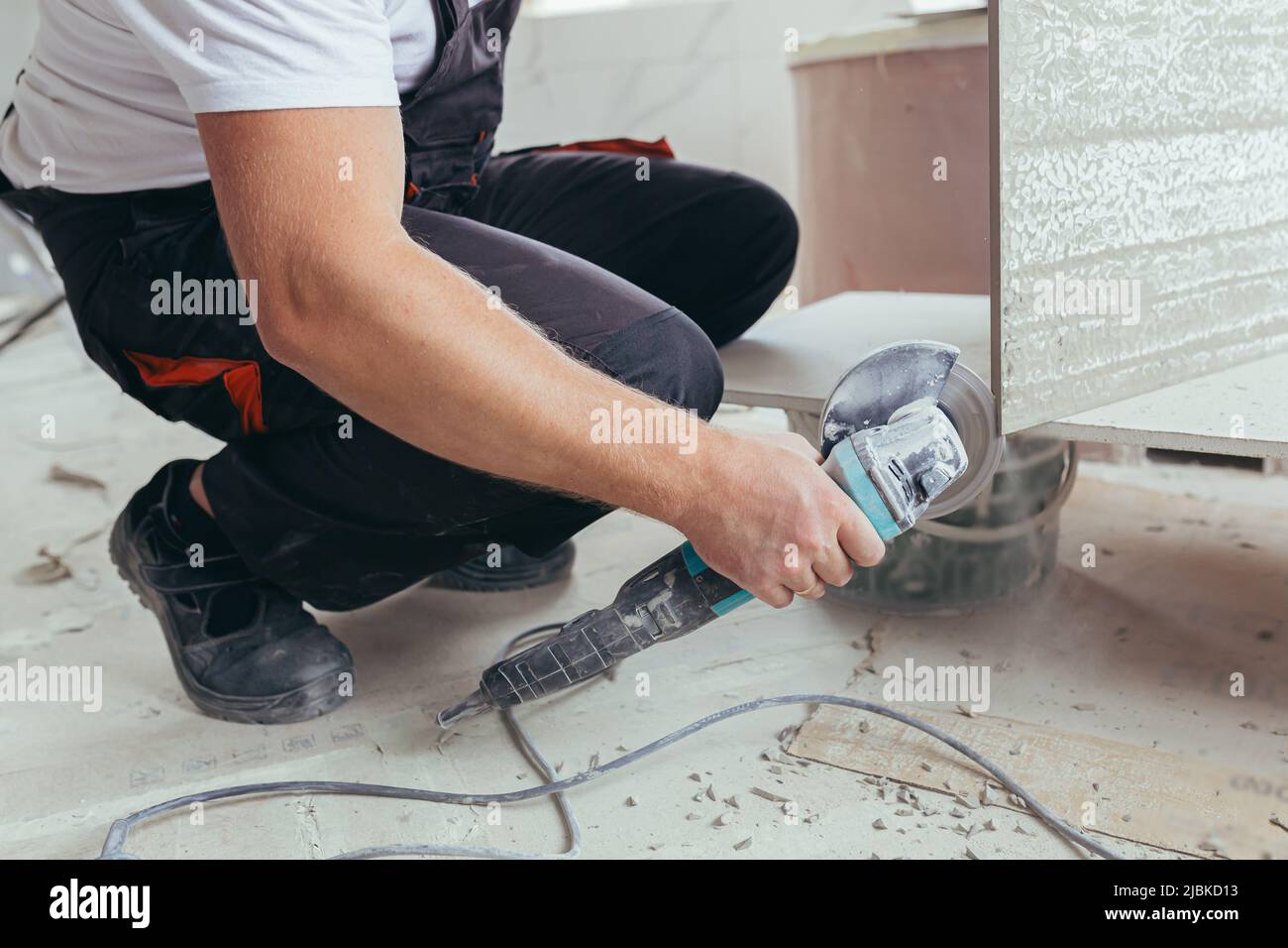 male worker cuts a large ceramic tile with an electric saw with a hand tool Stock Photo