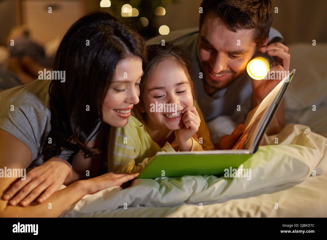 happy family reading book in bed at night at home Stock Photo Alamy