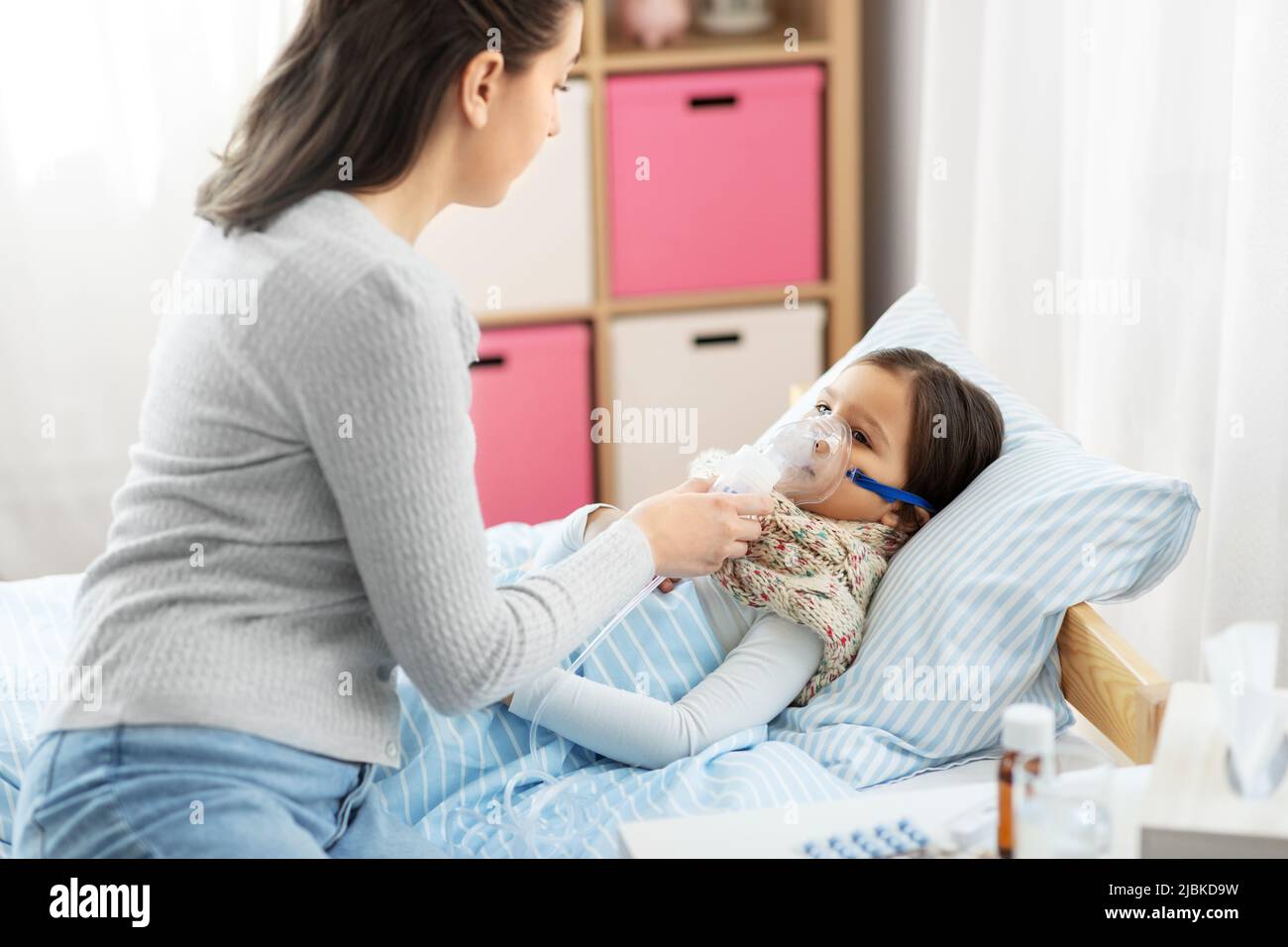 mother and sick daughter with oxygen mask in bed Stock Photo