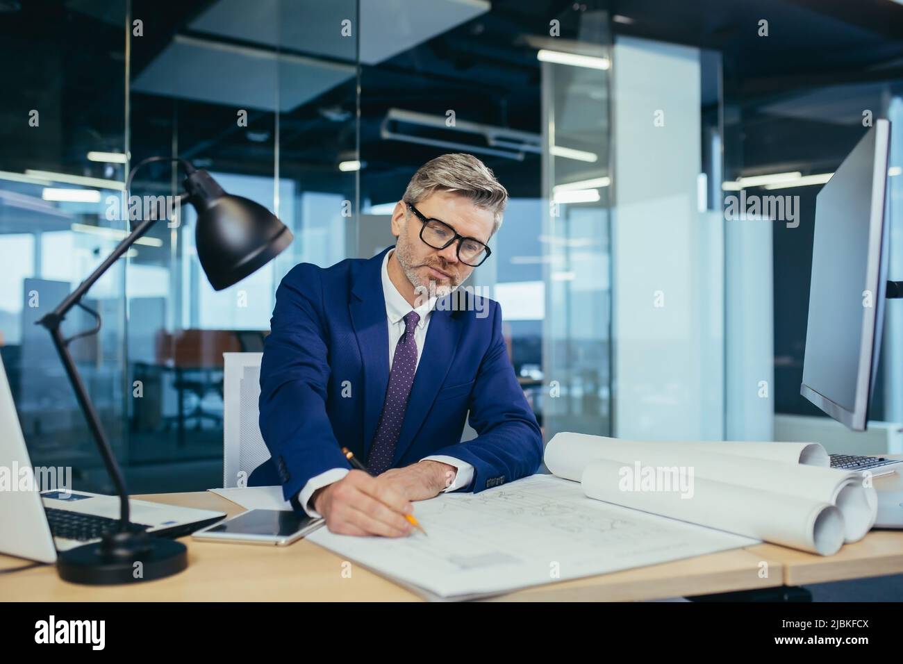 Successful and experienced male designer working in the office on the project, making adjustments to the layout plan Stock Photo