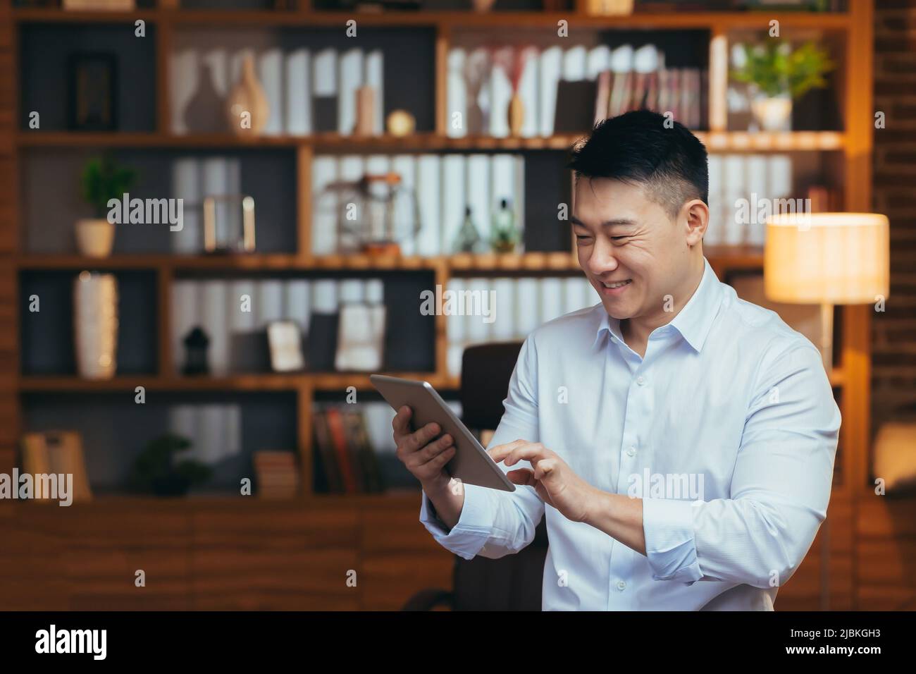 Asian relaxing at home after work, watching online video channel on tablet, smiling and rejoicing, business man reading e-book Stock Photo