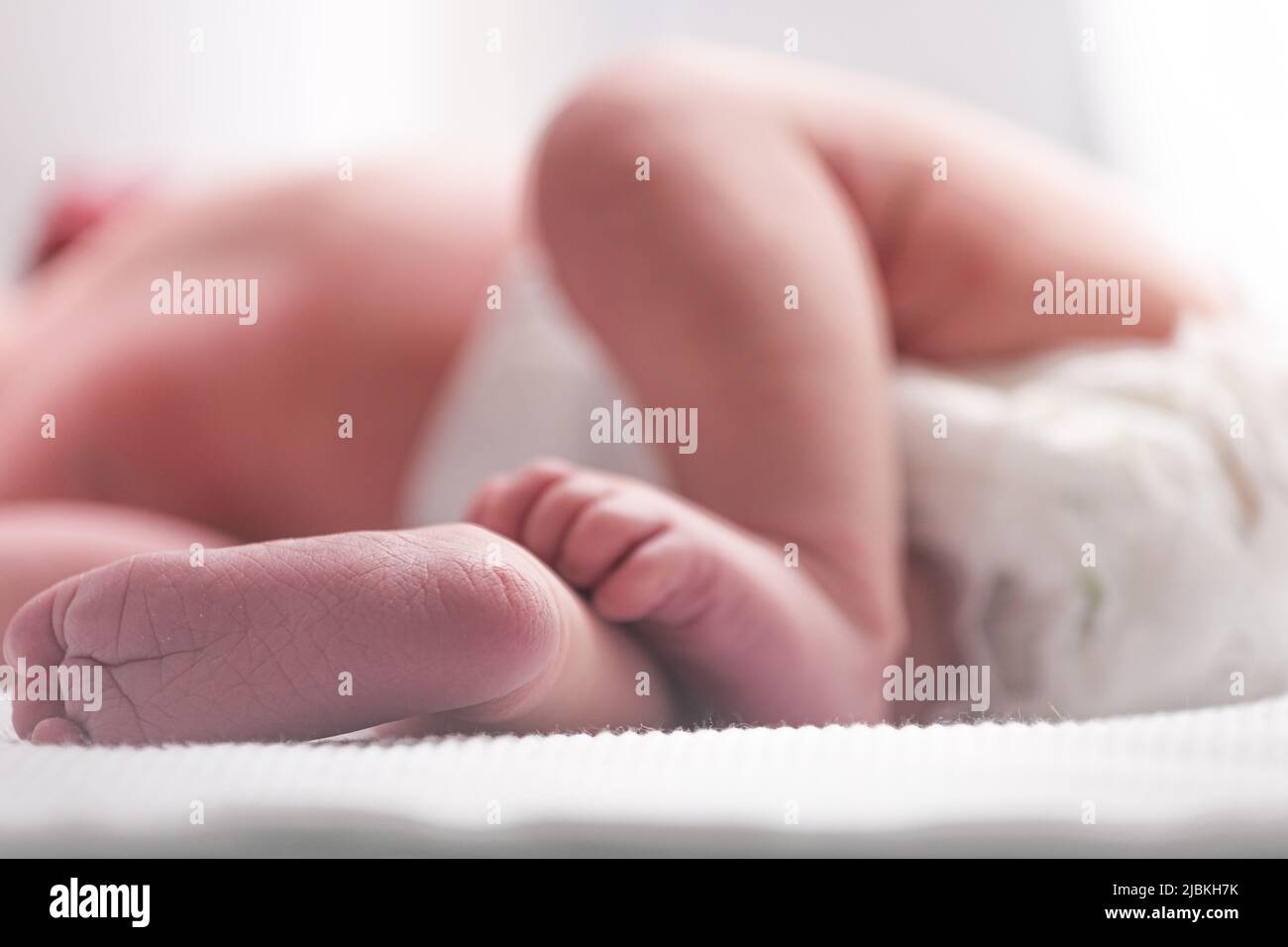 Sweet small feet of newborn baby on light blurred background. Stock Photo