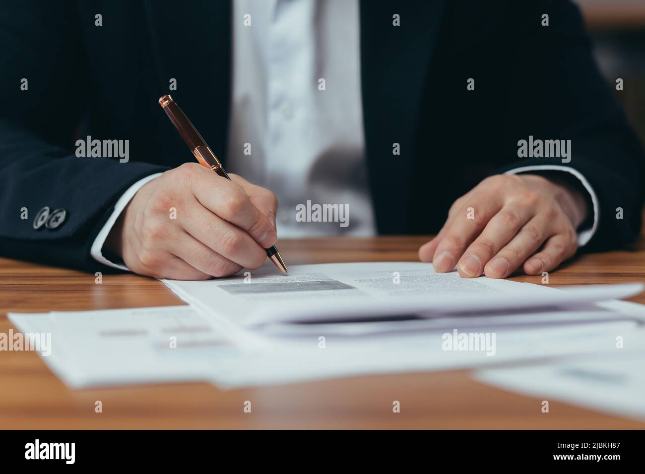 Close-up photo of Asian businessman's hands signing bank documents, man working in modern office, sitting at table, banker's paperwork Stock Photo