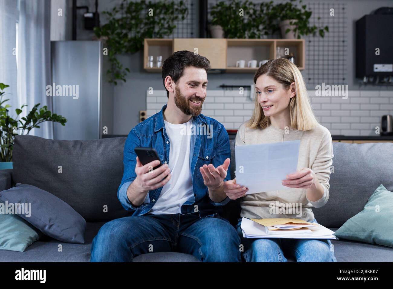 A man and a woman are happy at home, make online payments, using the