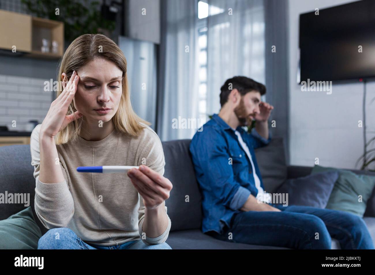 Sad man and woman sitting on the couch, disappointed with a negative
