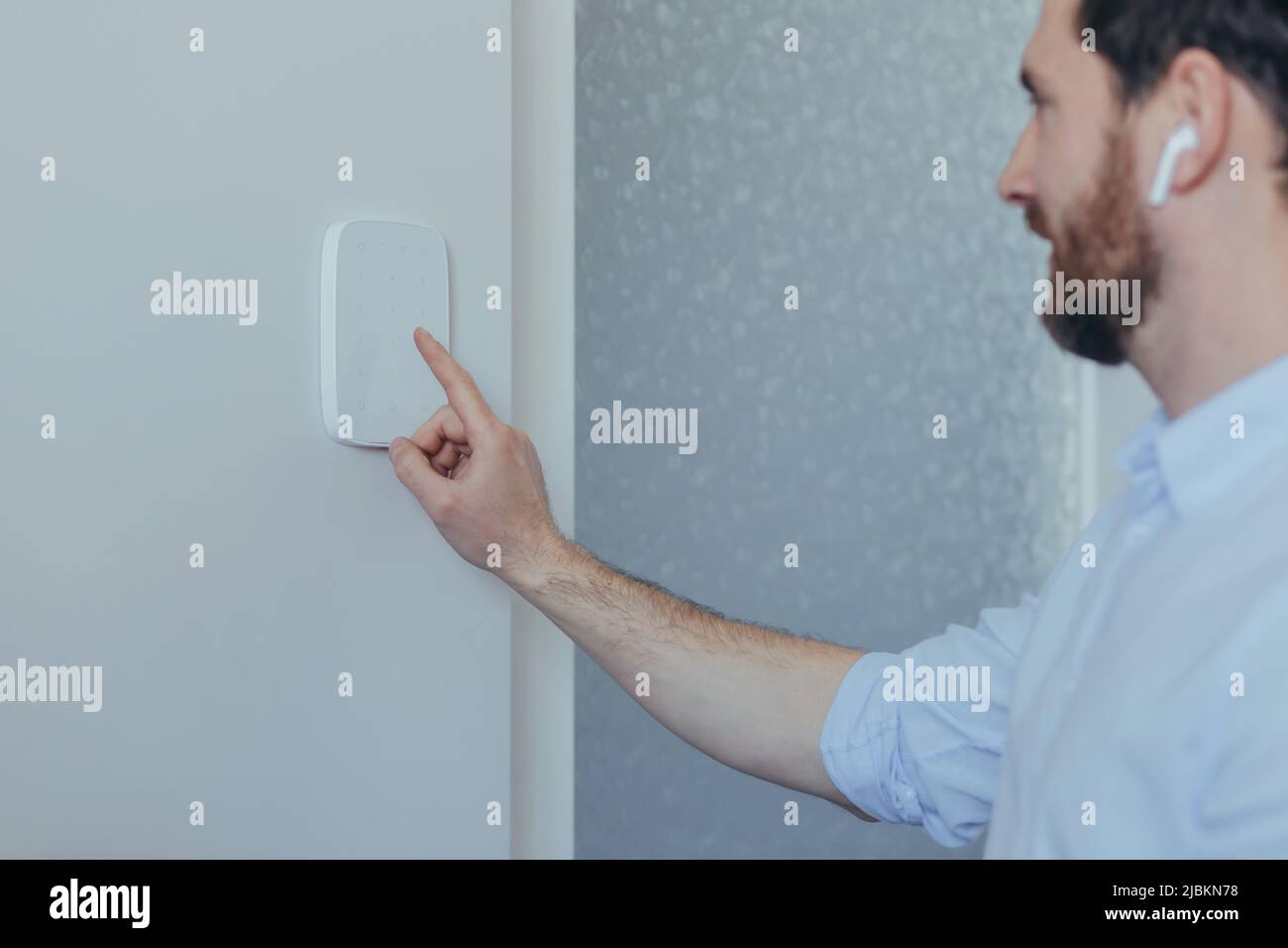 Businessman enters finger password lock code on alarm panel, on white