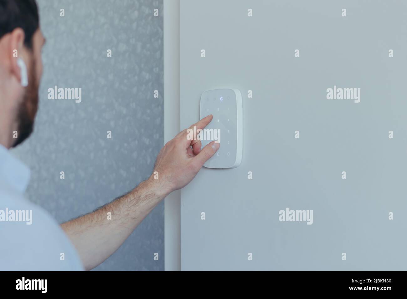 Businessman enters finger password lock code on alarm panel, on white