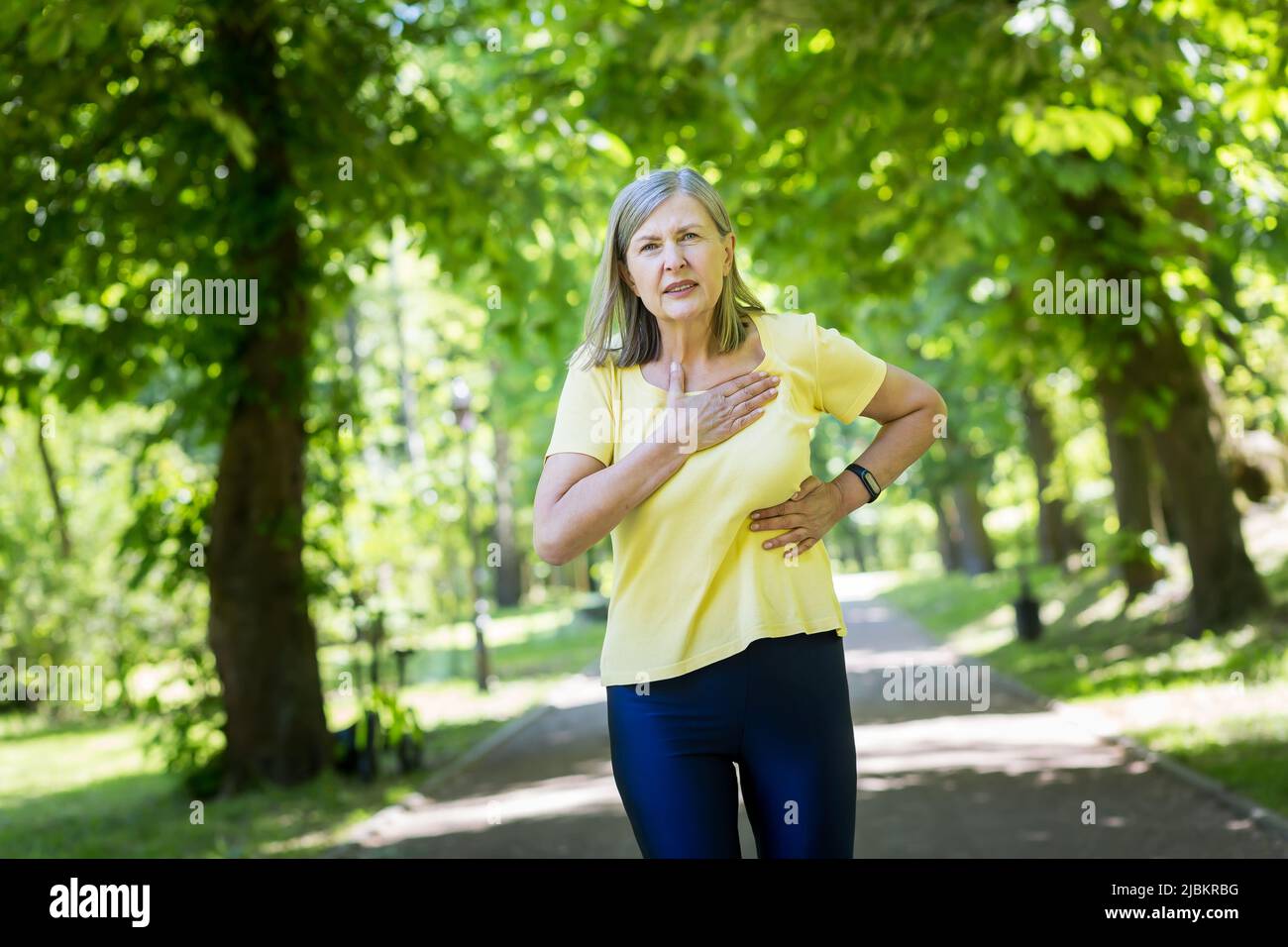 Senior grayhaired woman jogging in the park has severe chest pain
