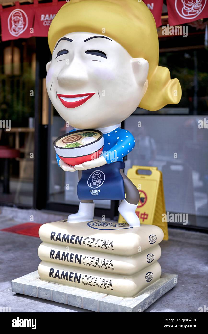Japanese restaurant exterior with large distinctive statue of a smiling waitress Stock Photo