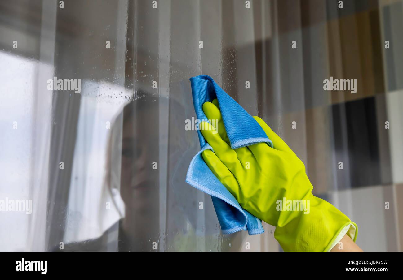 Wiping the window from dirt. Blue rag. Hand wipes the window. Stock Photo
