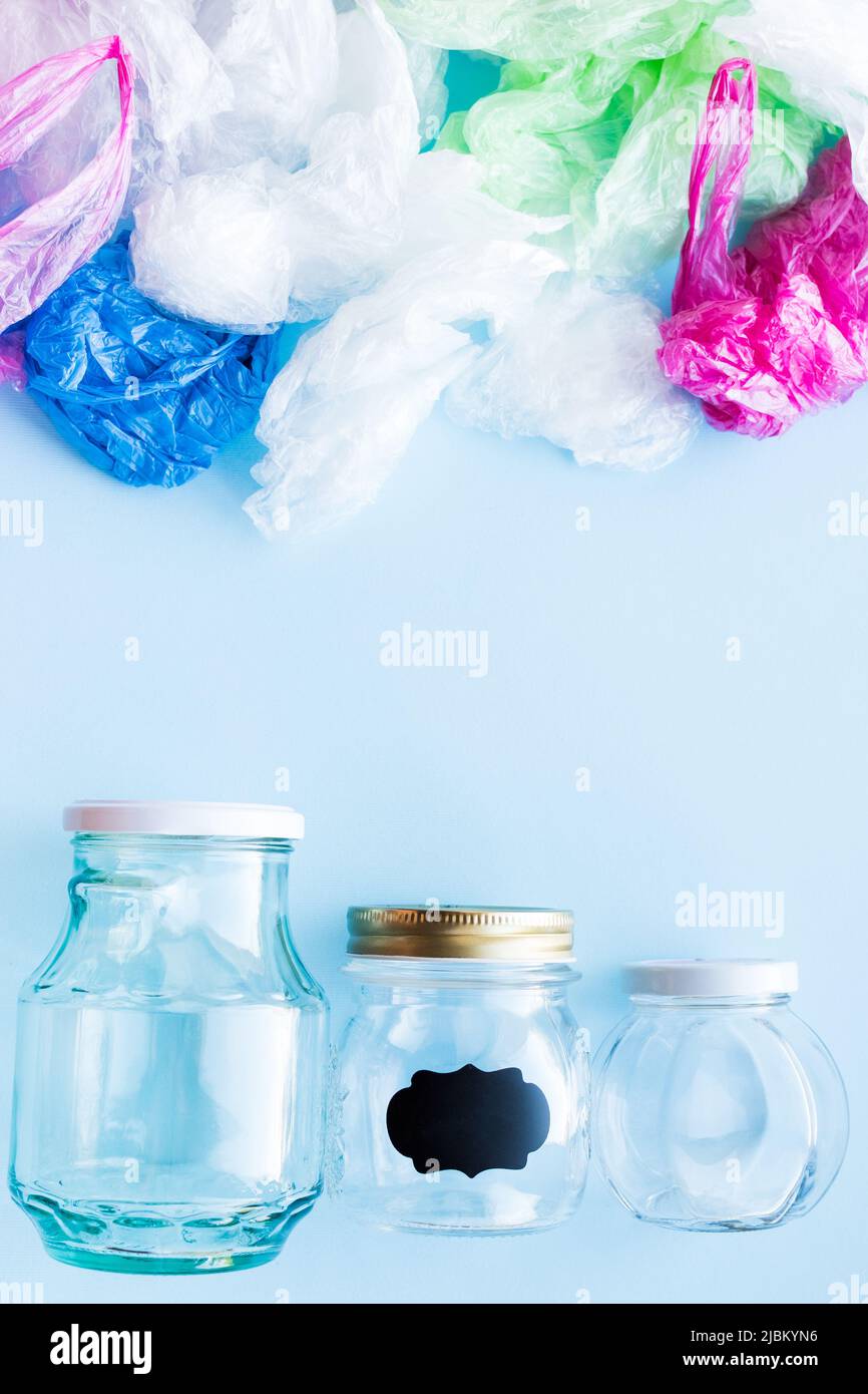 Many disposable plastic bags vs reusable glass jars on a blue background. Zero waste shopping